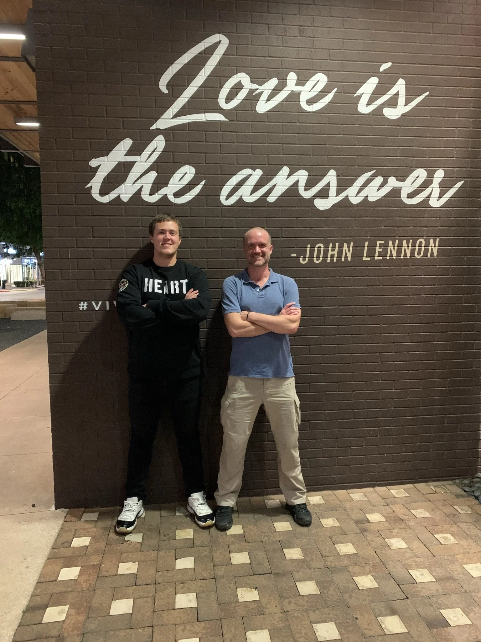 Kelly and Scott in front of a "Love is the answer" mural.